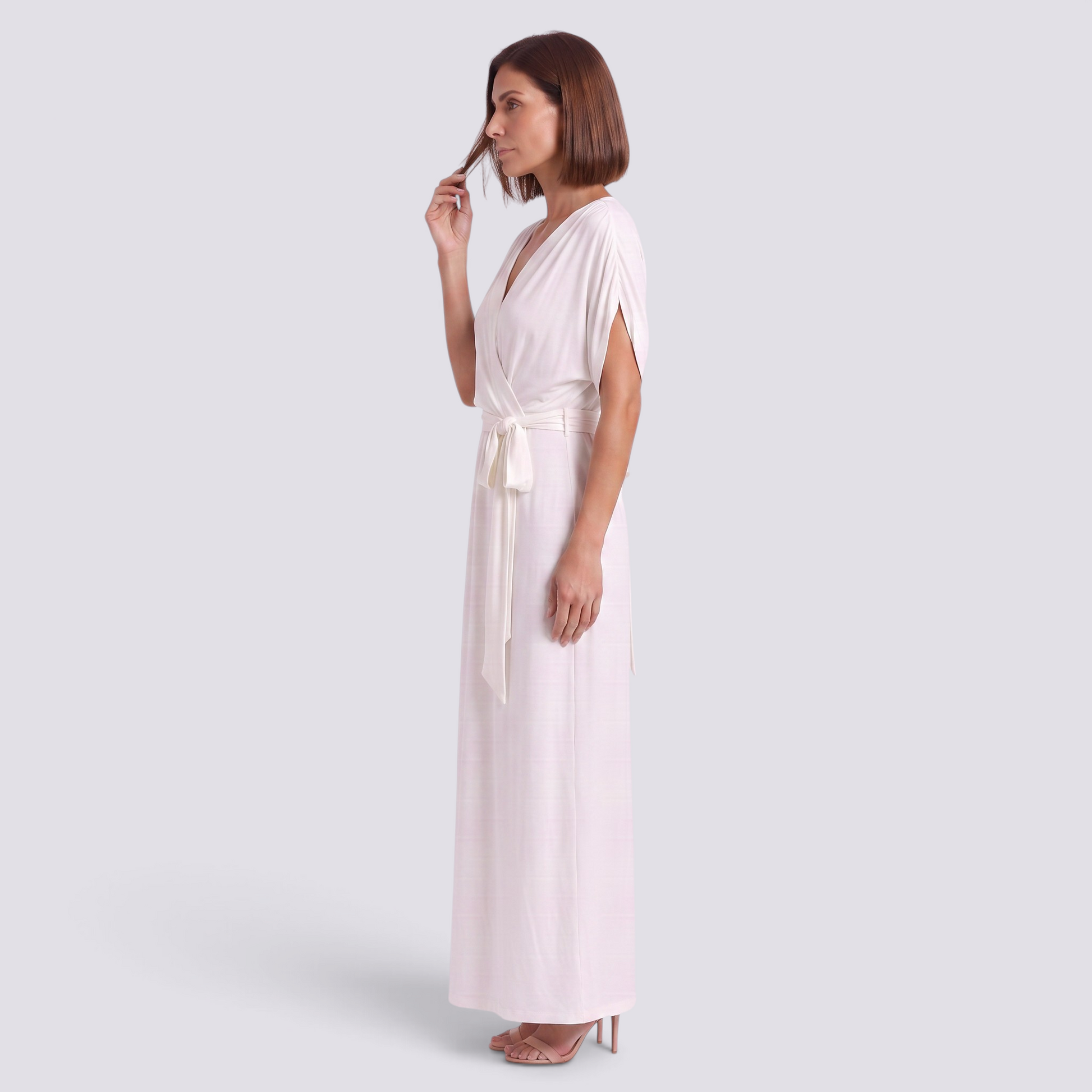 Essyro elegant floor-length cream wrap dress with delicate straps and a tie waist worn by a woman in profile view