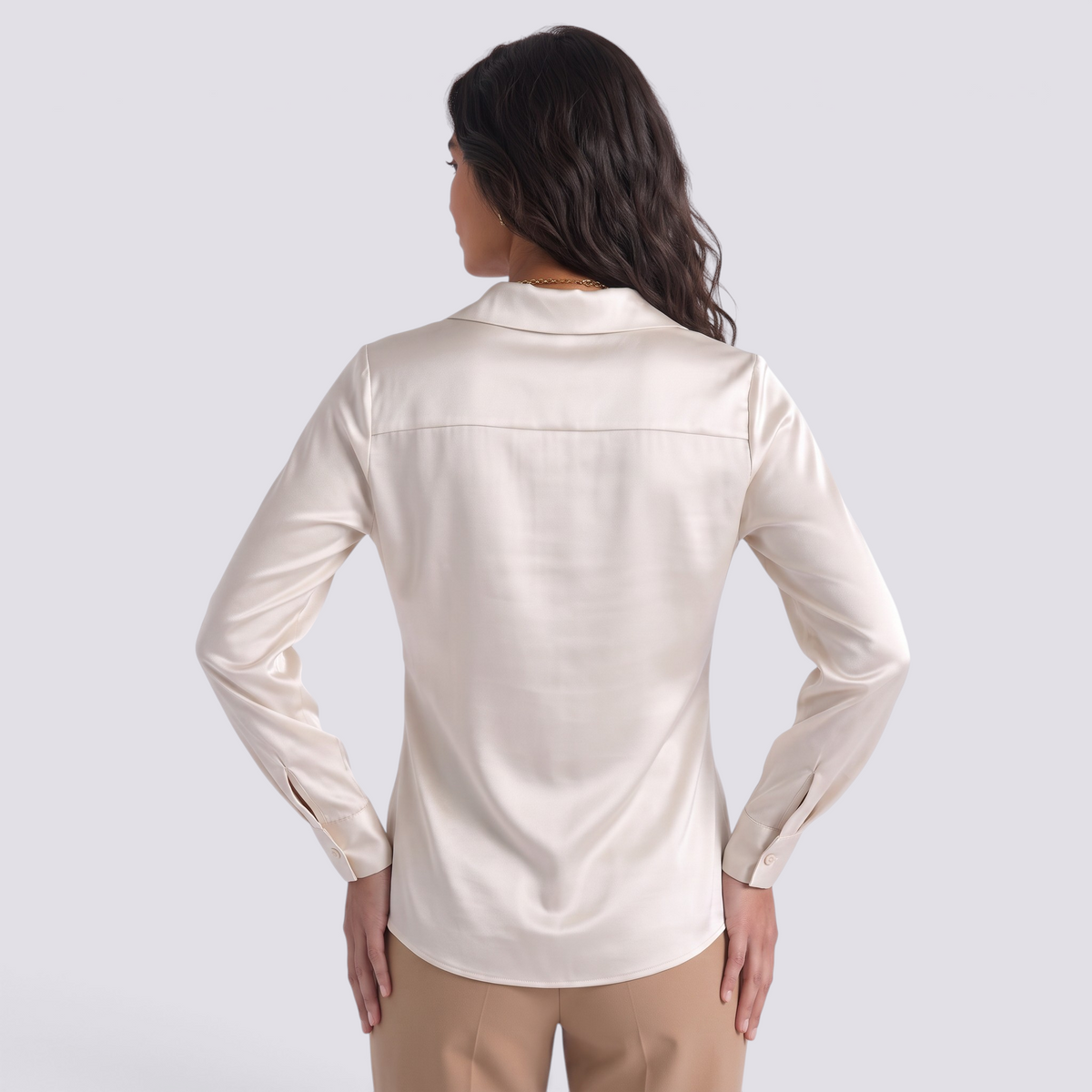 Back view of a woman wearing an Essyro cream satin blouse with long sleeves and a tailored fit.