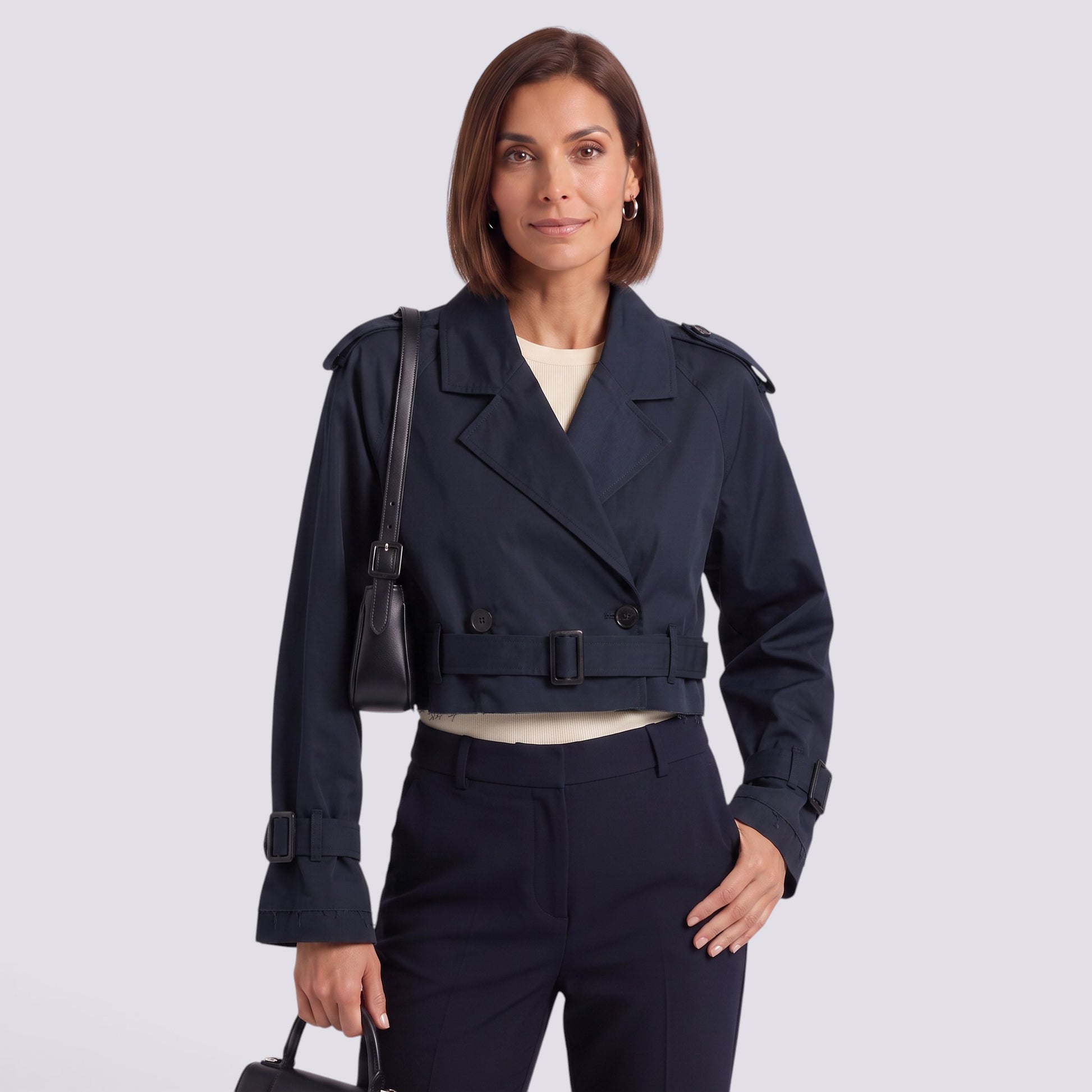 Essyro cropped navy windbreaker jacket with double-breasted design worn by a woman with a shoulder bag