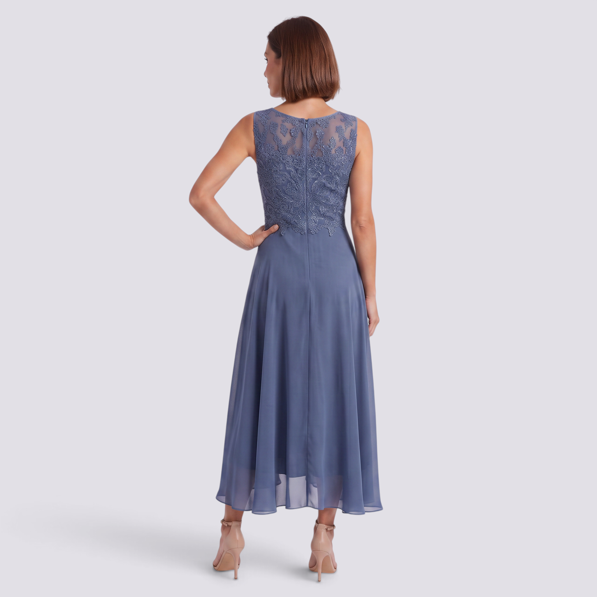 Essyro midi dress in dusty blue with intricate lace back detail and flowing skirt, worn by a woman from behind.