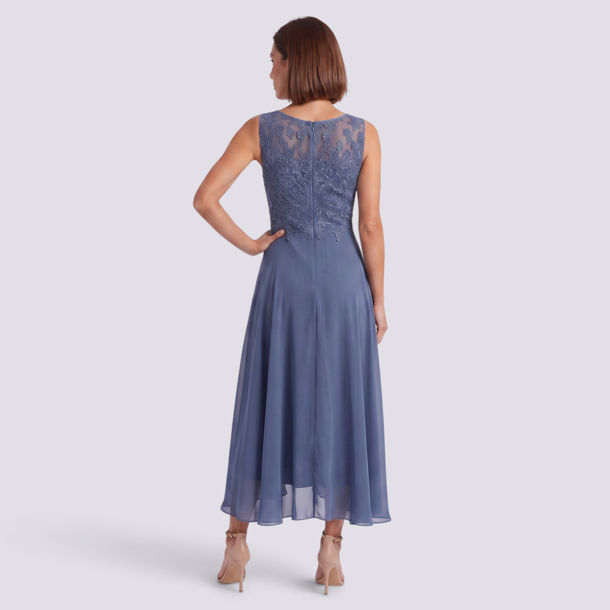 Essyro midi dress in dusty blue with intricate lace back detail and flowing skirt, worn by a woman from behind.