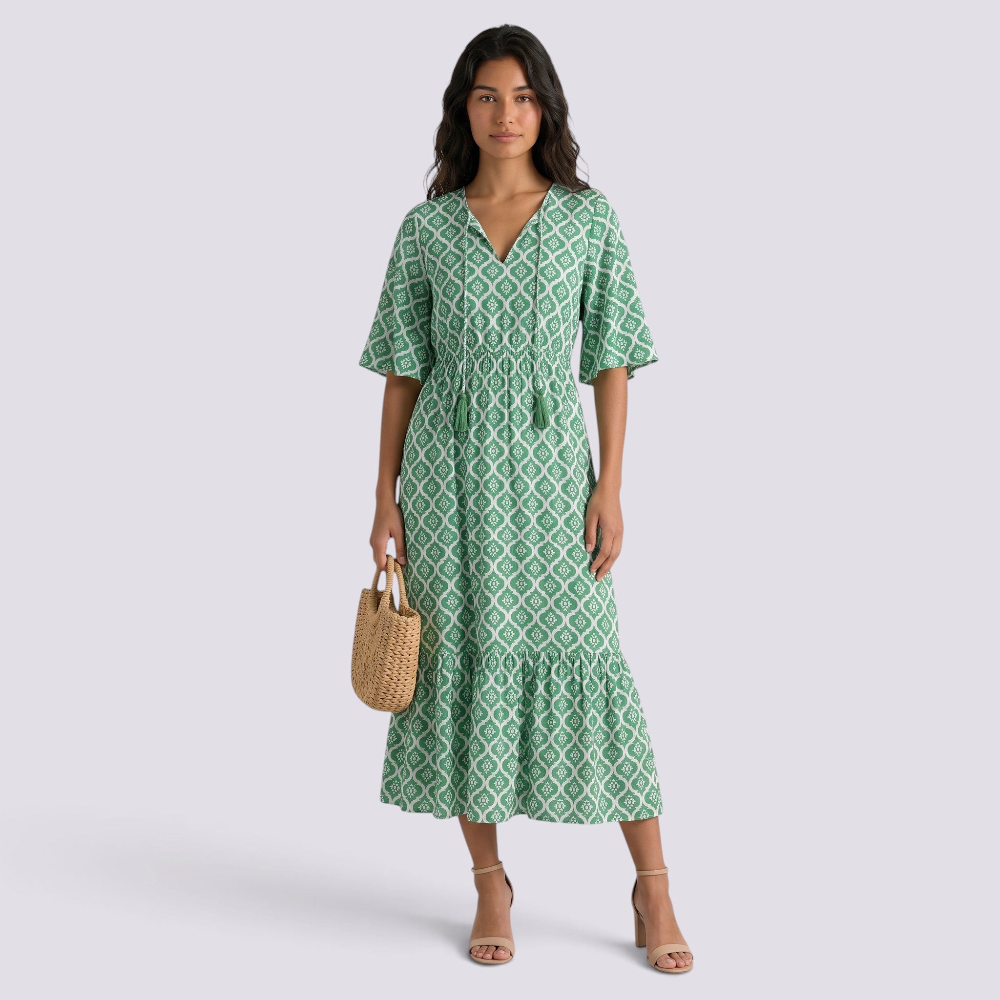 Essyro green boho maxi dress with V-neck, short sleeves, and geometric print worn by a model with a straw bag.