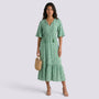 Essyro green boho maxi dress with V-neck, short sleeves, and geometric print worn by a model with a straw bag.