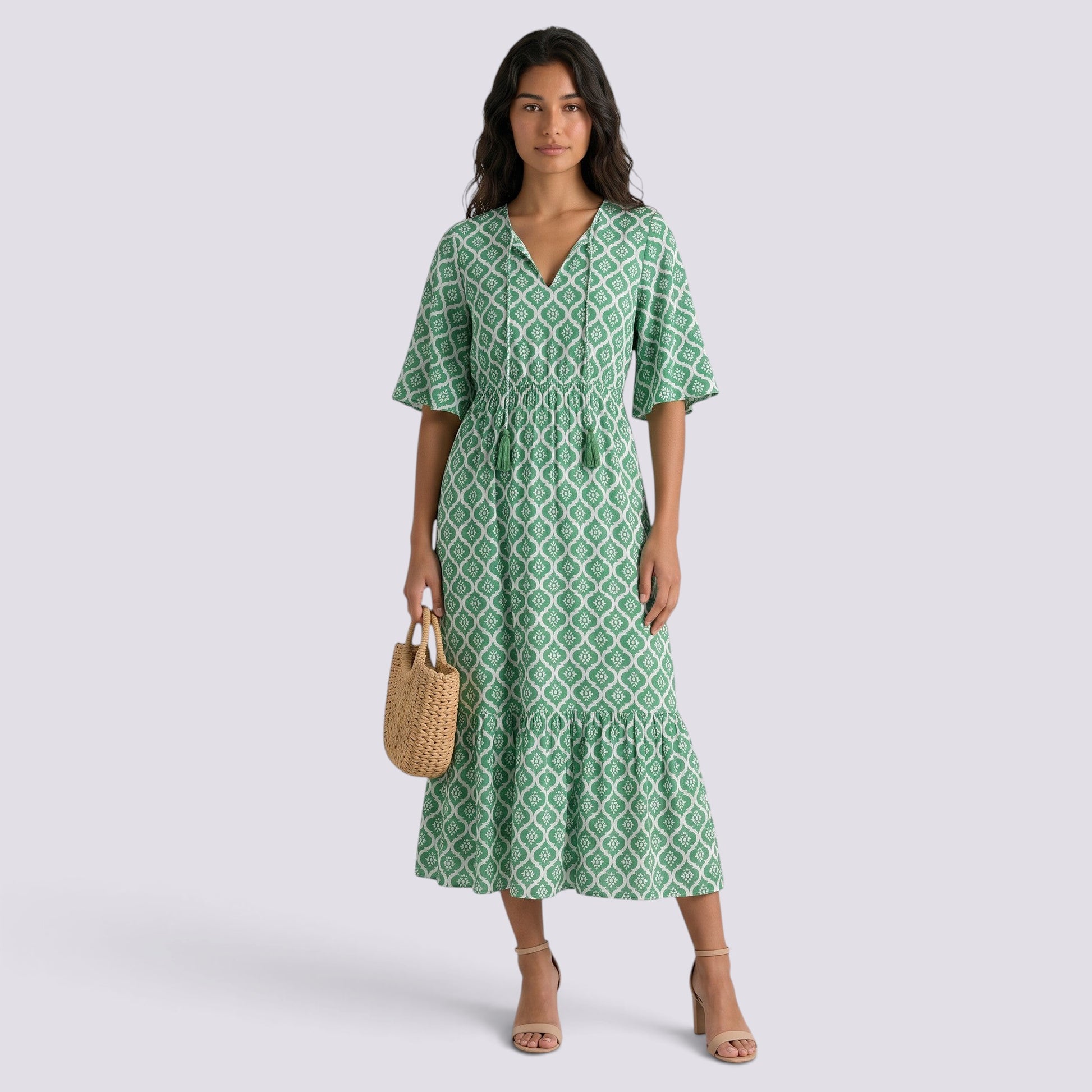 Essyro green boho maxi dress with V-neck, short sleeves, and geometric print worn by a model with a straw bag.