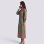 Essyro midi A-line dress in green with artistic print, V-neck, and 3/4 sleeves worn by a model, side profile view.