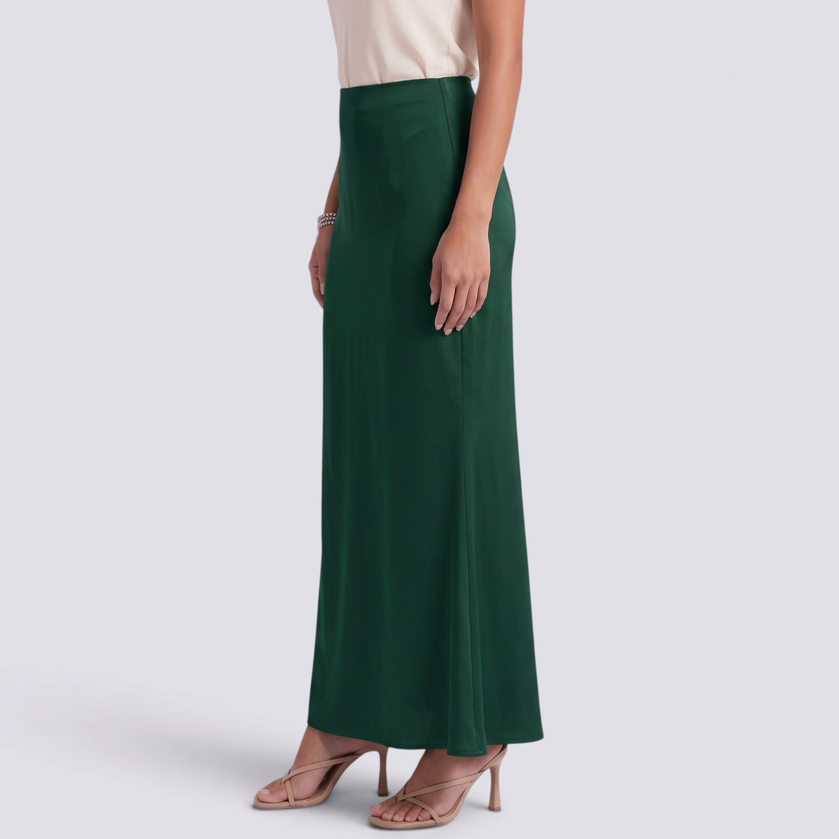 Essyro high-waisted forest green satin mermaid maxi skirt worn with a beige top and strappy heels, side view