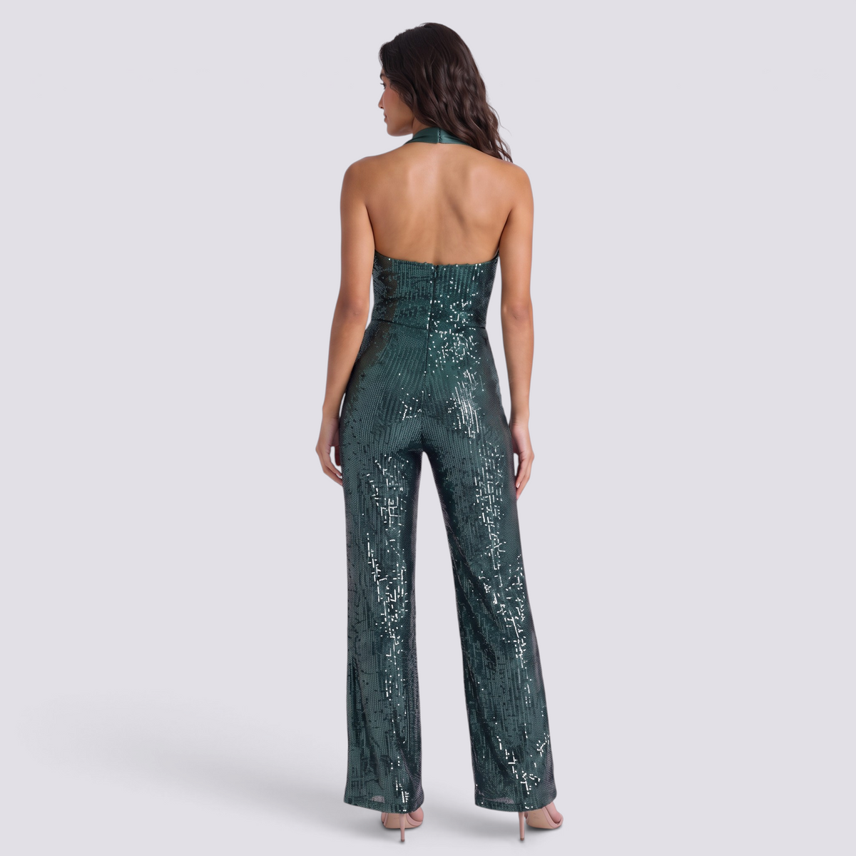 Essyro back view of a dark green sequin jumpsuit with a halter neck and open back design on a model