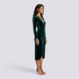 Essyro emerald green velvet midi dress with long sleeves, V-neck, and draped waist on a model, side profile view.