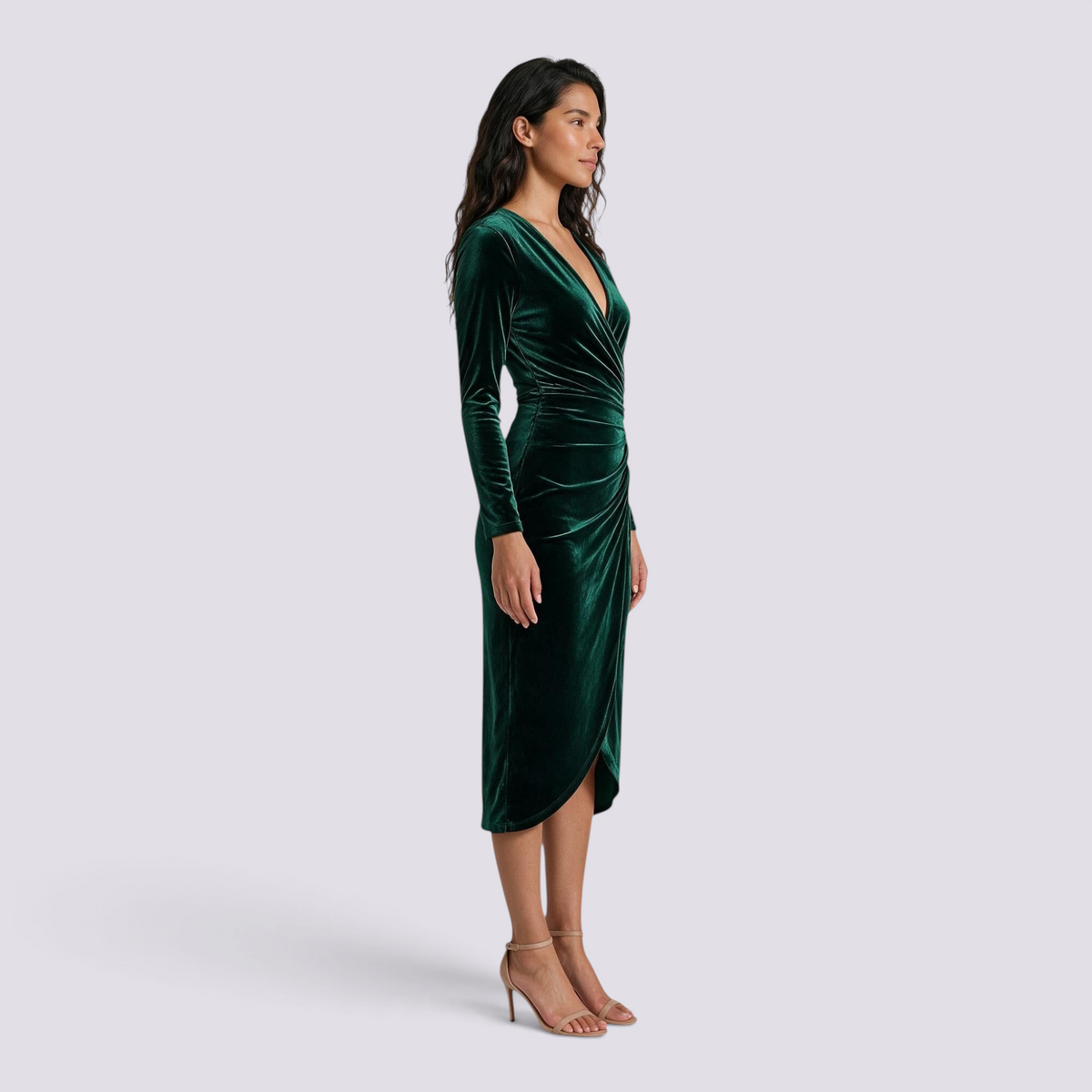 Essyro emerald green velvet midi dress with long sleeves, V-neck, and draped waist on a model, side profile view.