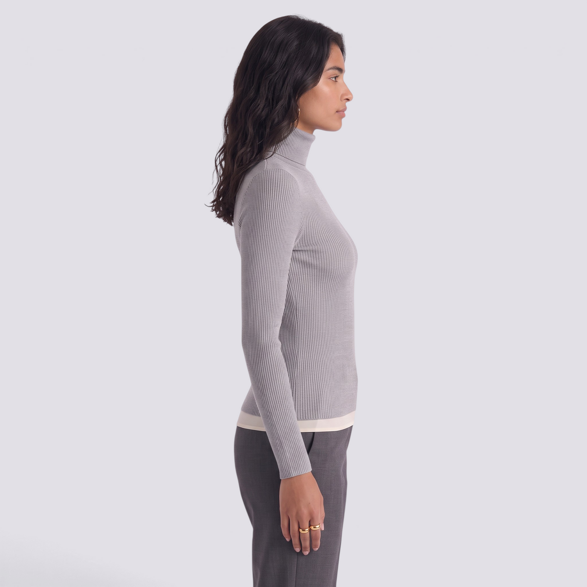 Essyro grey ribbed turtleneck sweater with long sleeves worn by a model in a side profile view.