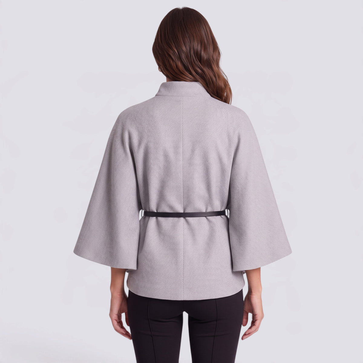 Back view of Essyro short grey cape with high collar, batwing sleeves, and a thin black belt, worn over black pants.