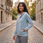 Essyro light blue velvet hooded jacket with button front worn by a smiling woman on a cobblestone street in Paris