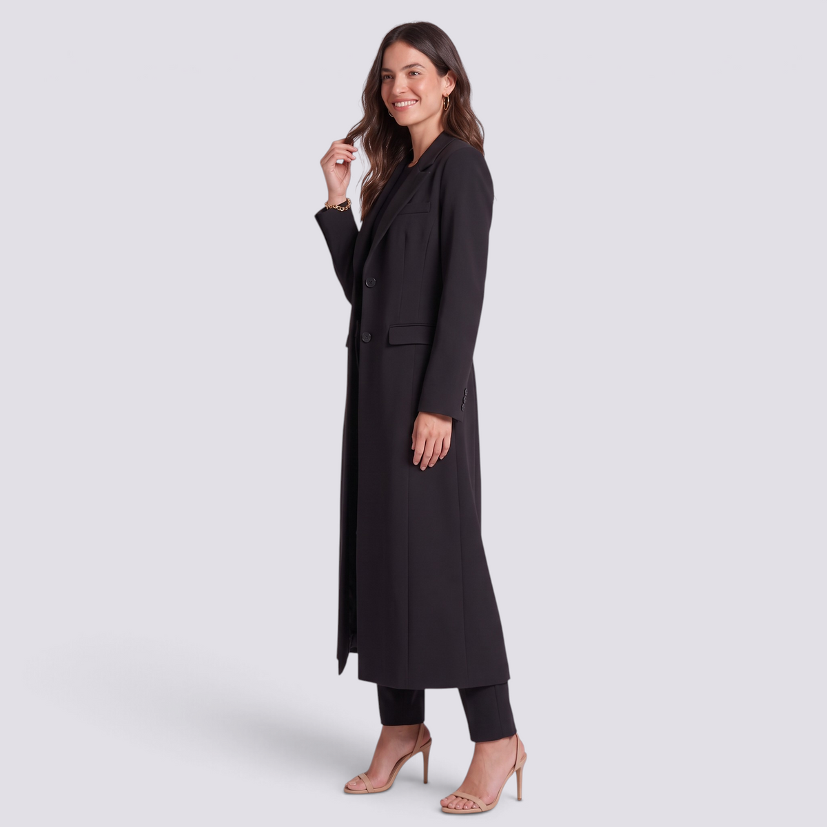 Essyro elegant black long coat with wide lapels and button closure worn by a smiling woman in heels