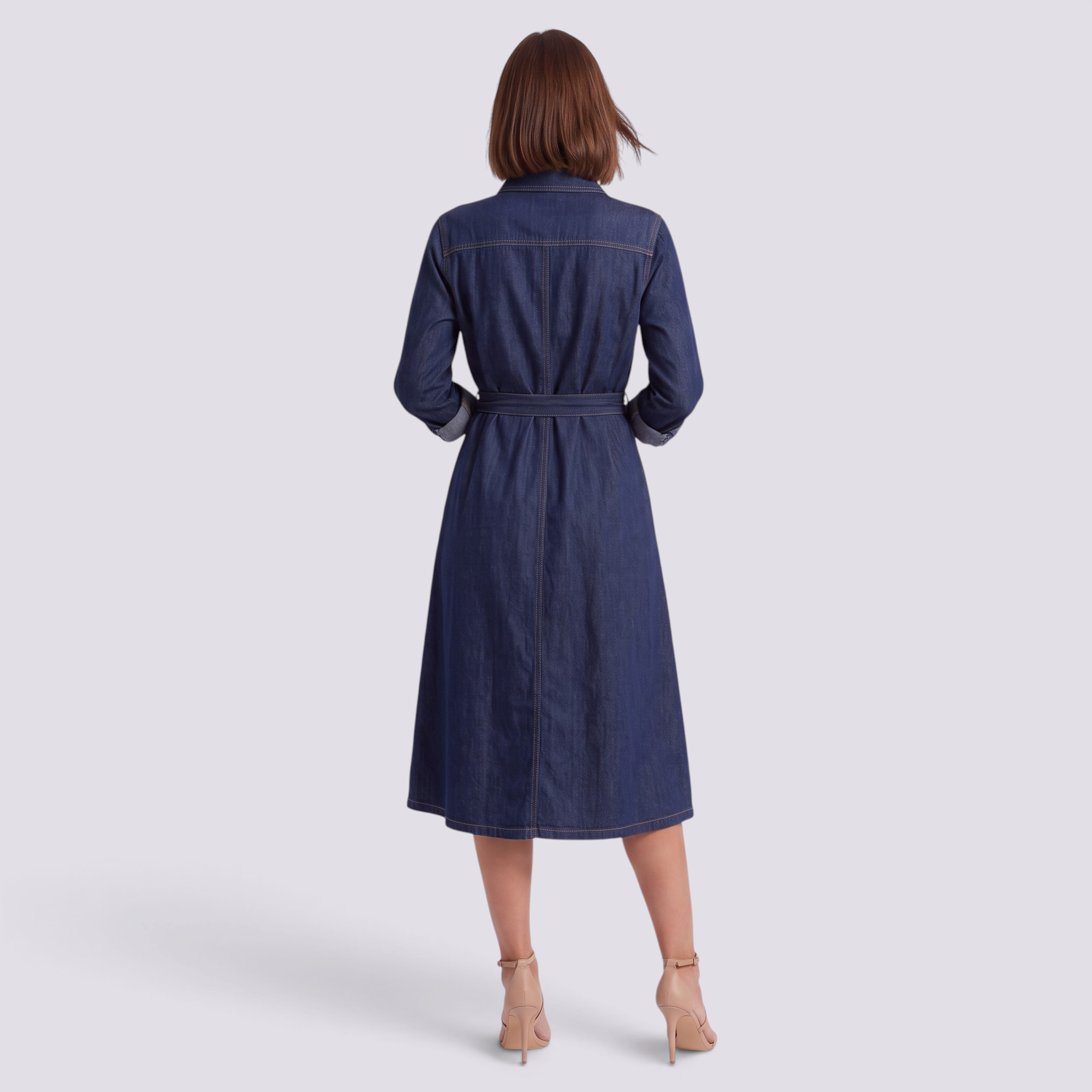 Back view of a woman wearing an Essyro long denim shirt dress with a waist belt and flared skirt in dark blue denim.
