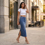 Essyro long fitted denim skirt in vintage wash blue with a side slit, worn by a woman with a white crop top.
