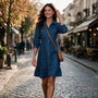 Essyro long-sleeve denim shirt dress with a button-down front, cinched waist, and ruffled hem worn on a city street.