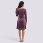 Back view of a woman wearing an Essyro mauve velvet short dress with long sleeves and a flattering flared cut.