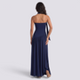 Back view of a woman wearing an Essyro navy blue halter neck maxi dress with an asymmetrical draped skirt
