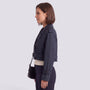 Essyro navy blue cropped windbreaker jacket with belted cuffs and collar worn by a woman in a side profile view