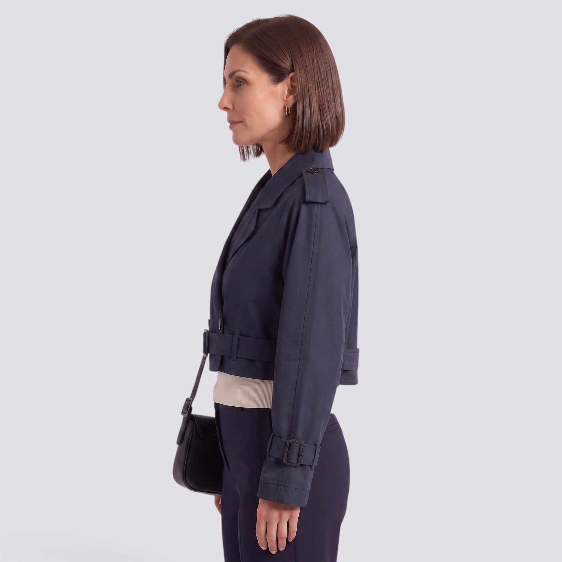 Essyro navy blue cropped windbreaker jacket with belted cuffs and collar worn by a woman in a side profile view