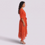 Essyro orange maxi dress with V-neck, batwing sleeves, and asymmetrical hem worn by a model in profile view.