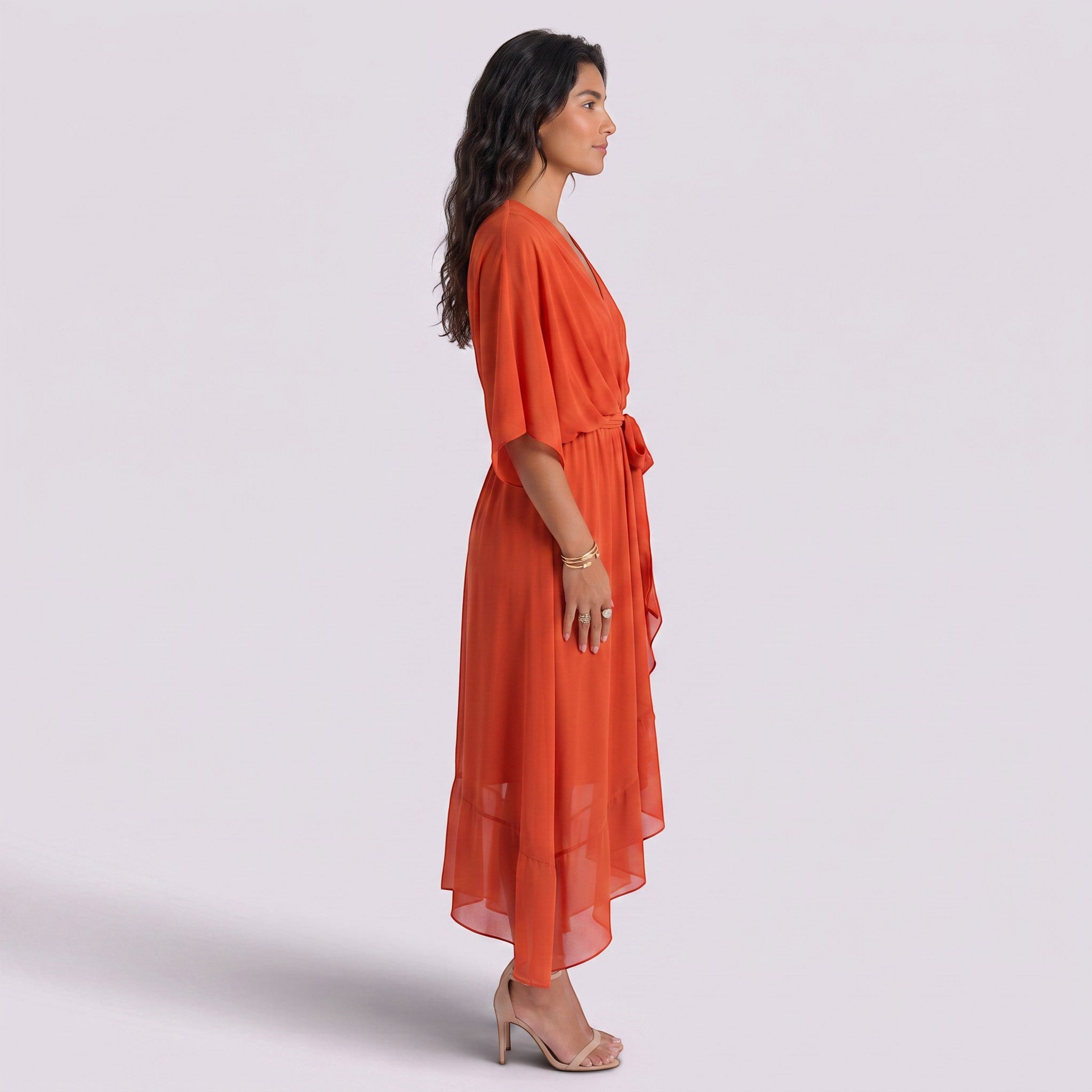 Essyro orange maxi dress with V-neck, batwing sleeves, and asymmetrical hem worn by a model in profile view.