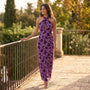 Essyro purple floral maxi dress with halter neck and front cutout worn by a smiling woman on a sunny terrace