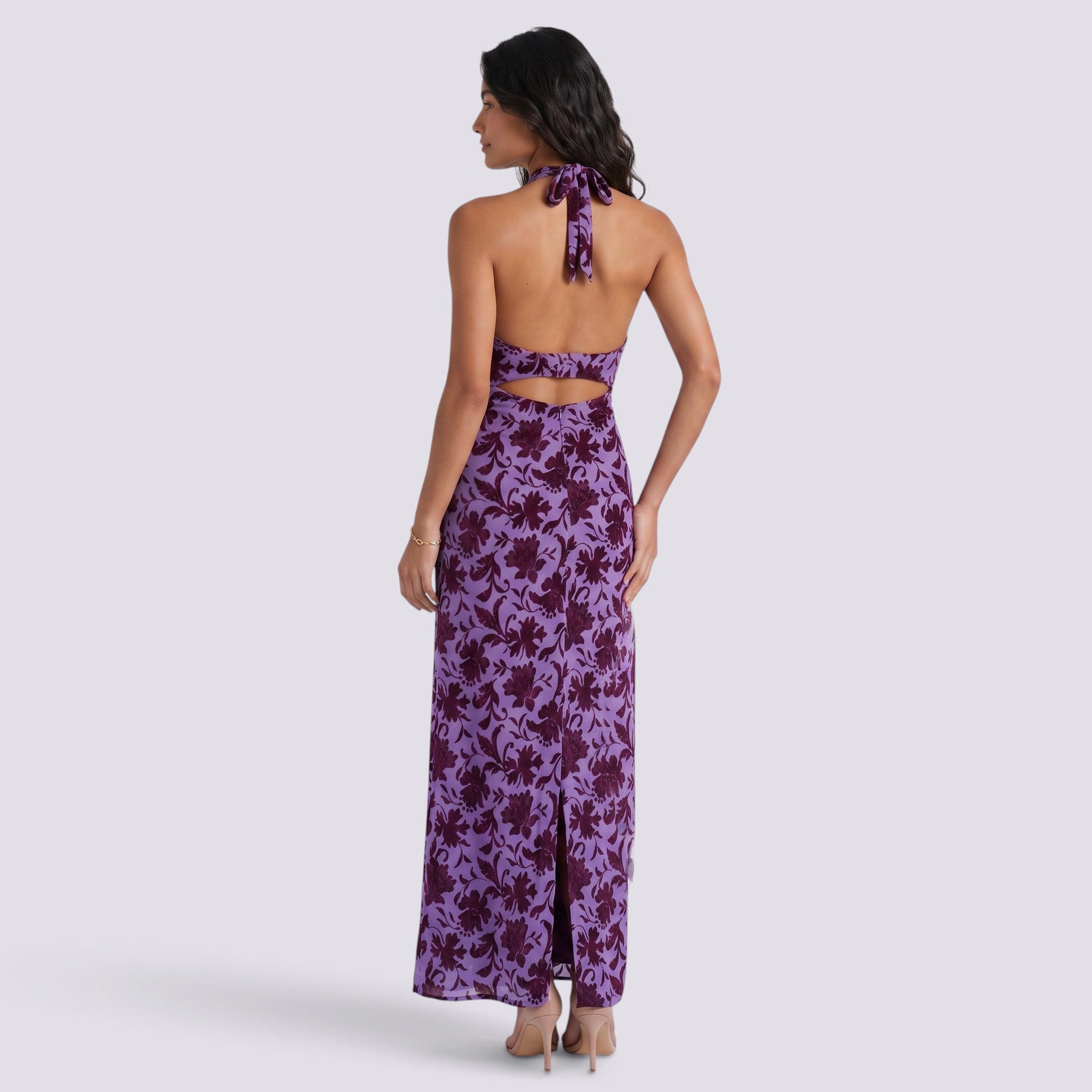 Essyro purple floral maxi dress with halter neck, open back, and side slit worn by a model, back view.