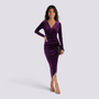 Essyro purple velvet midi dress with long sleeves, v-neck wrap design, and side slit worn by a smiling model