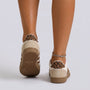 Essyro retro low-top sneakers in beige with leopard print heel detail, worn by a model with a silver anklet.