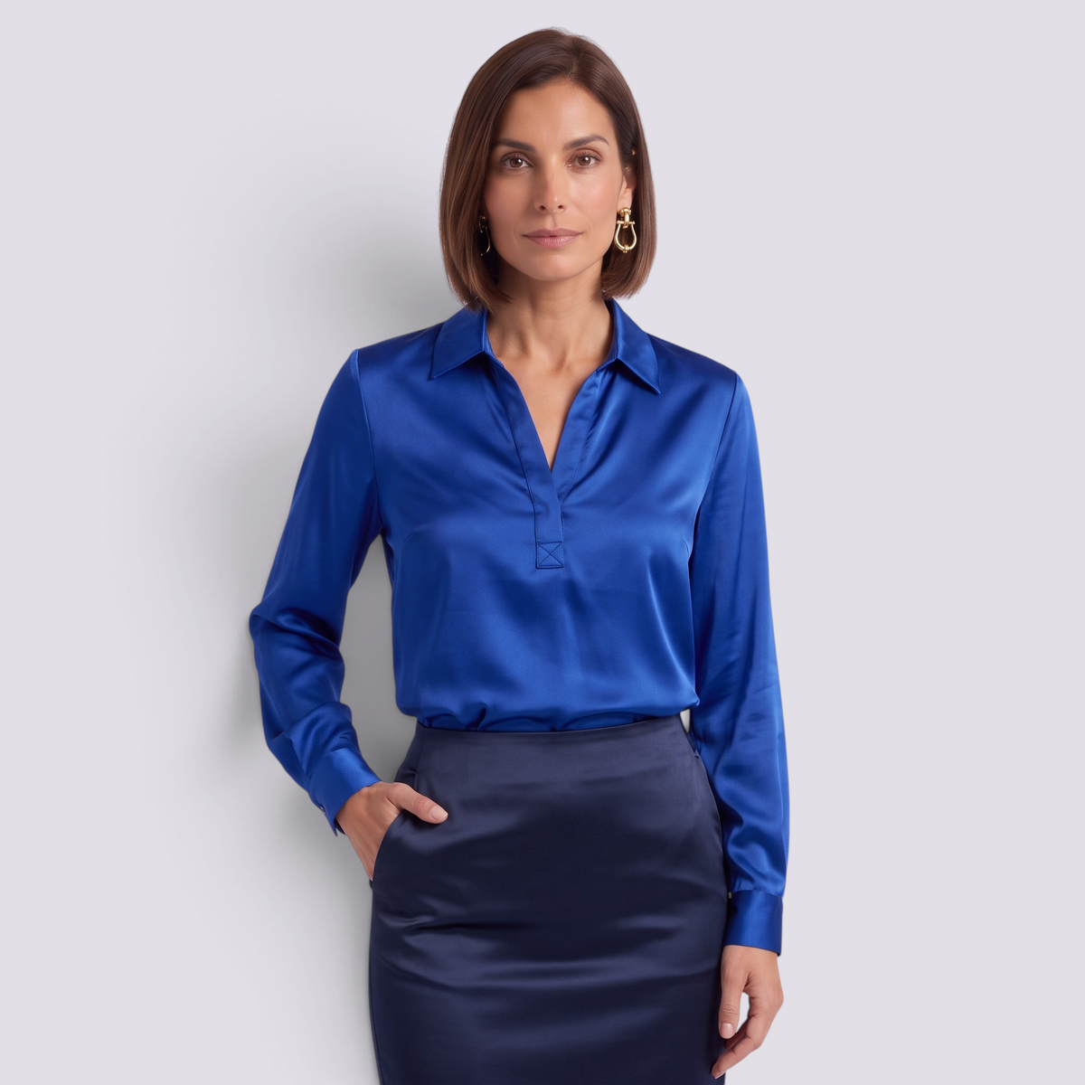 Essyro royal blue satin long-sleeve blouse with a V-neck, worn by a woman with a dark blue skirt
