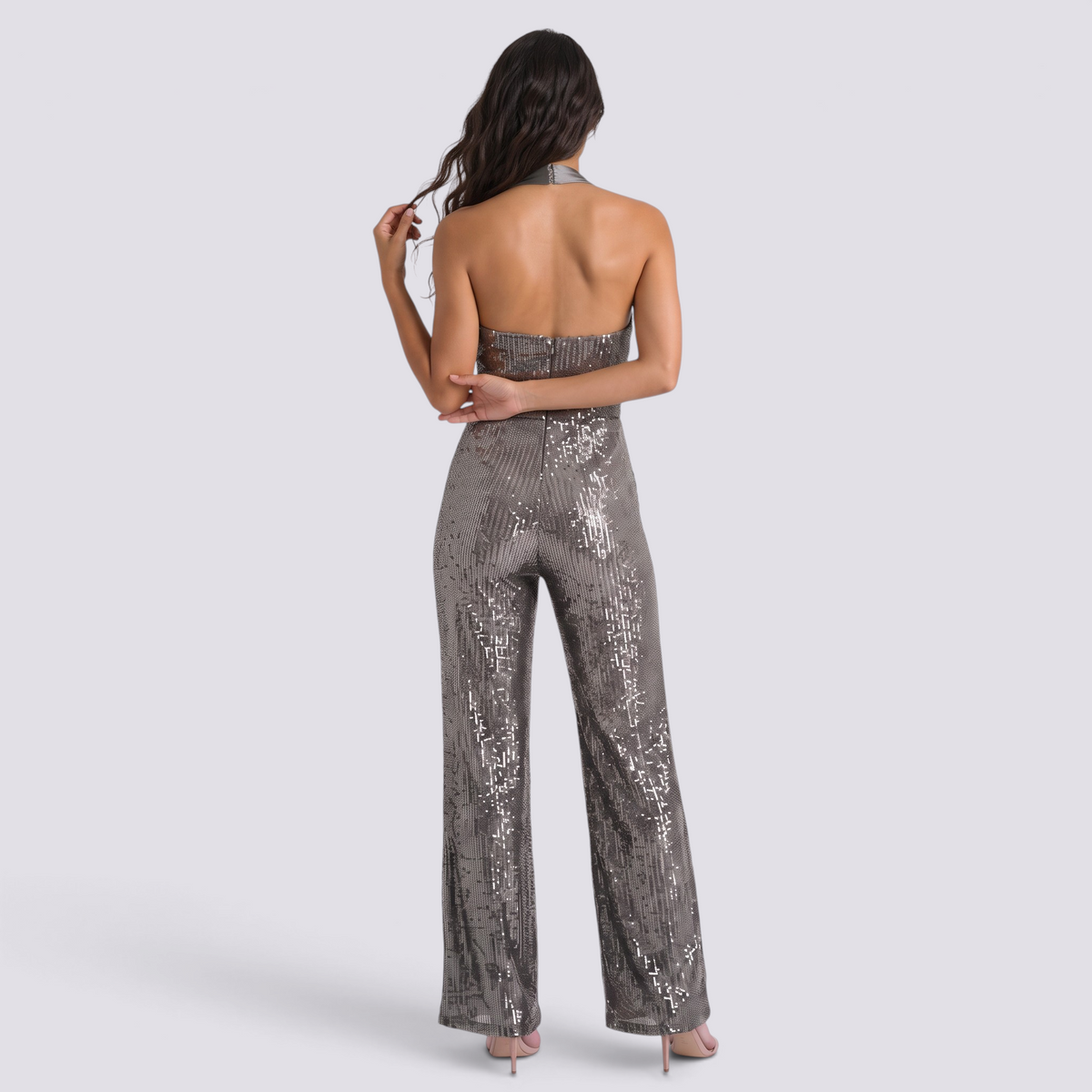 Essyro back view of a silver sequin halter neck jumpsuit with wide legs and an open back on a model