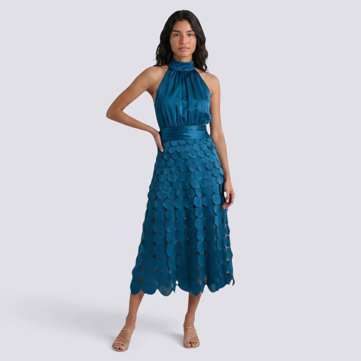 Essyro teal midi dress with halter neck and geometric disc skirt worn by a model on a plain background