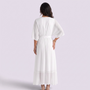 Back view of a woman wearing an Essyro white maxi dress with batwing sleeves, V-neck, and a cinched waist.