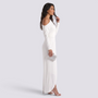 Essyro white one-shoulder jumpsuit with long draped sleeve and wide-leg wrap design worn by a model with a clutch