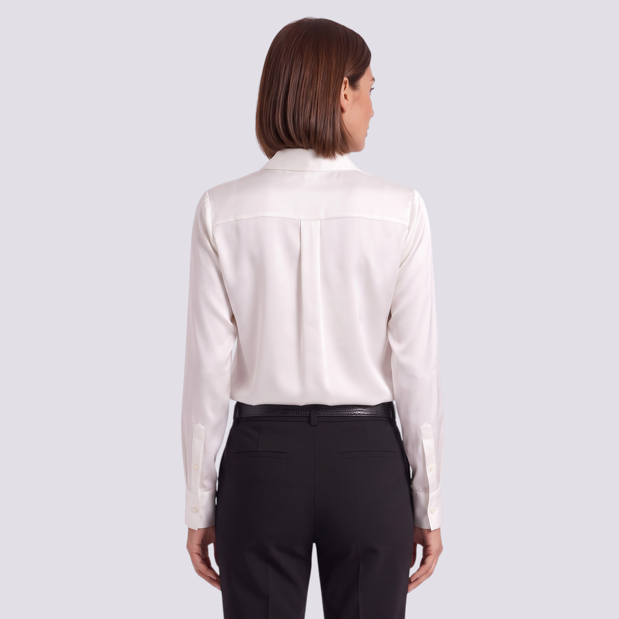 Back view of an Essyro white satin long-sleeve shirt tucked into black trousers on a woman with short brown hair.