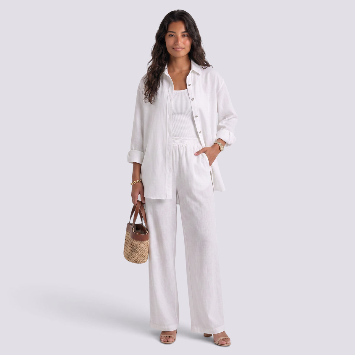 Essyro white two-piece set with a loose long-sleeve shirt and wide-leg trousers worn by a woman holding a straw bag.