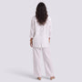 Back view of a woman wearing an Essyro white two-piece set with a loose long-sleeve shirt and wide-leg trousers.