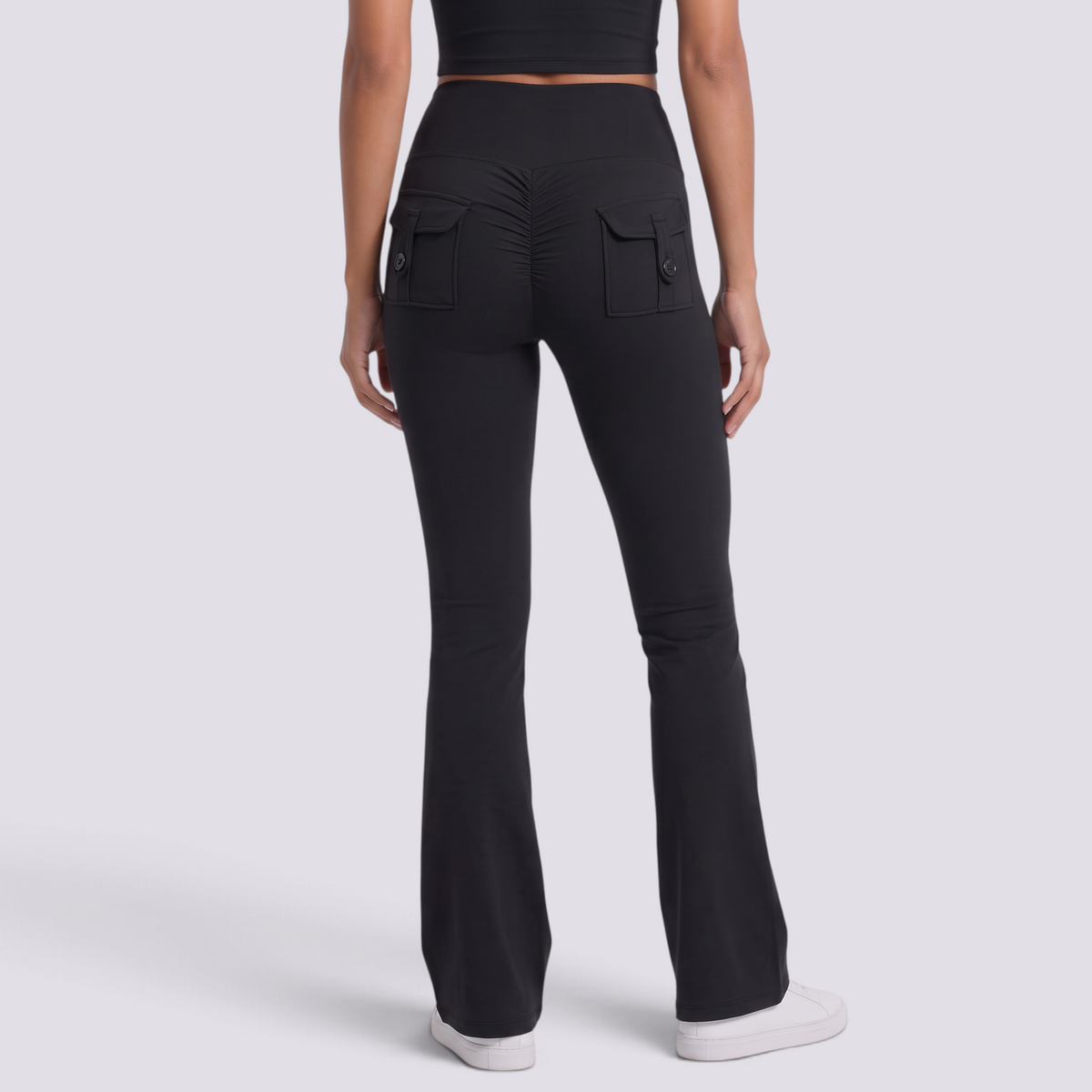 Mujer con leggings acampanados con bolsillos en negro, vista trasera con bolsillos