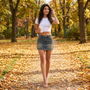 Mujer paseando por un parque en otoño con minifalda vaquera tiro bajo azul vintage