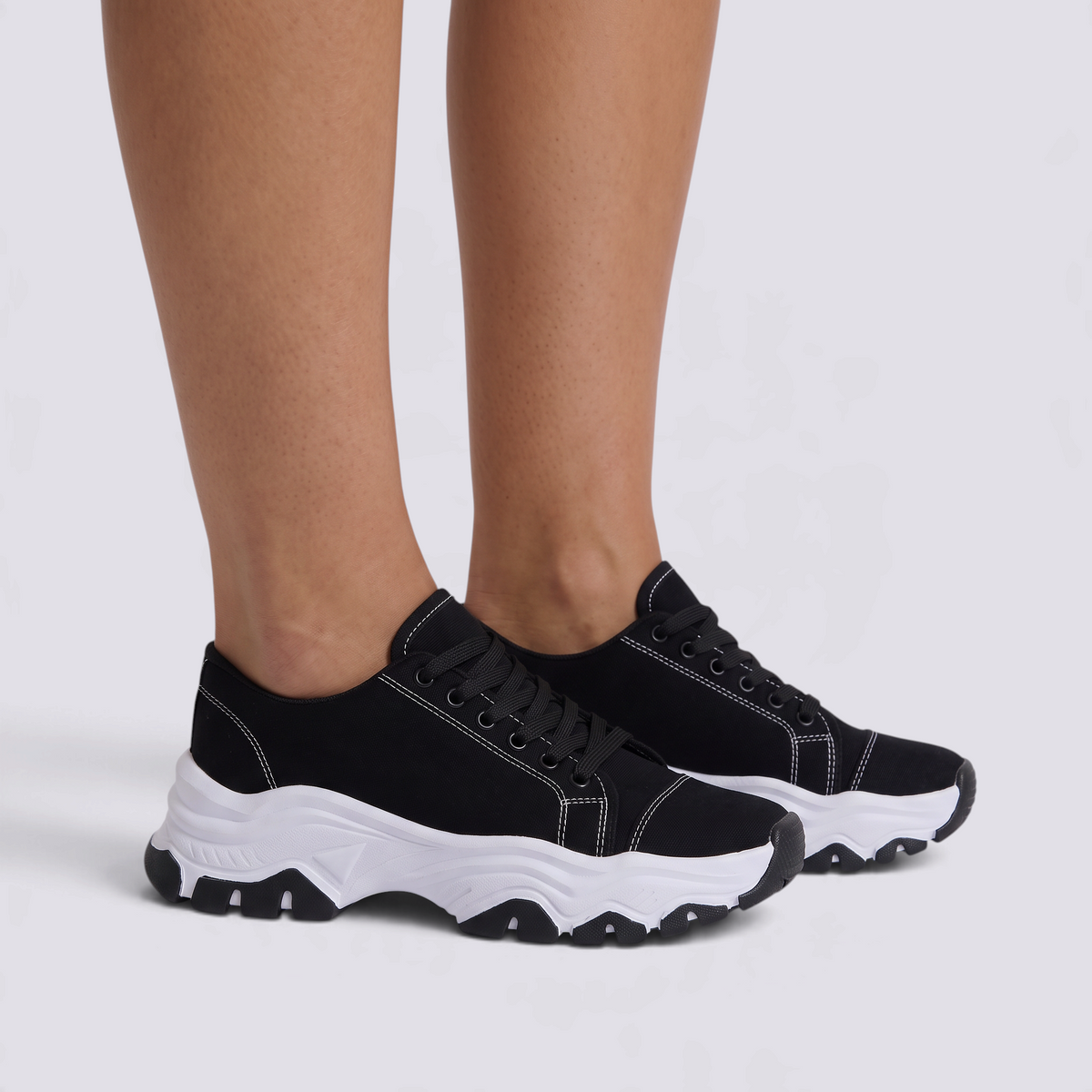 Zapatillas deportivas de mujer negras con suela ondulada y cordones, vista lateral