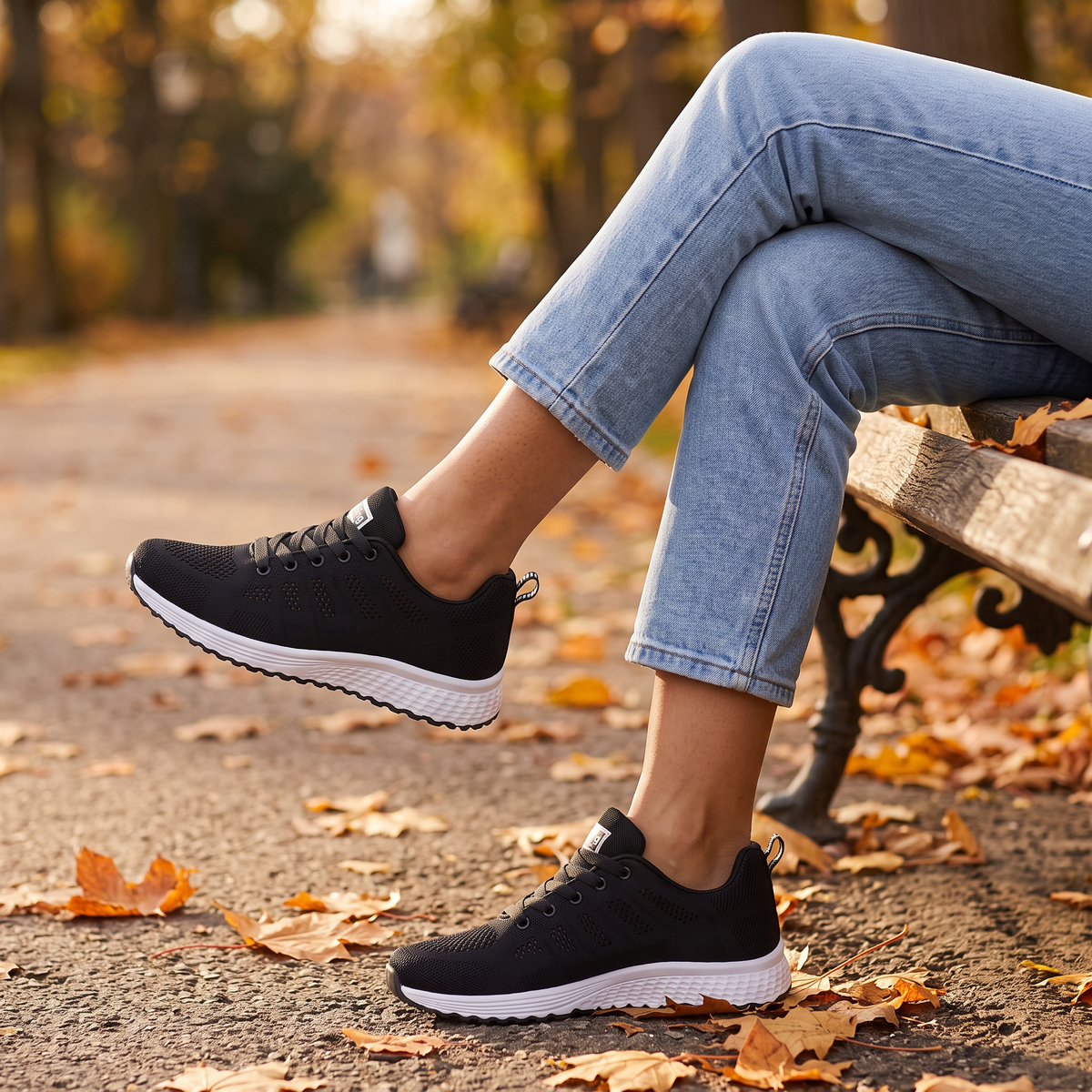 Zapatillas deportivas mujer de malla negras con cuña baja, sentada en un banco del parque en otoño