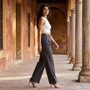 Mujer con pantalón gris oscuro de pierna ancha y pinzas paseando bajo los soportales