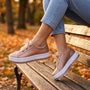 Zapatillas de plataforma con cordones de cinta puestas sobre un banco de parque en otoño