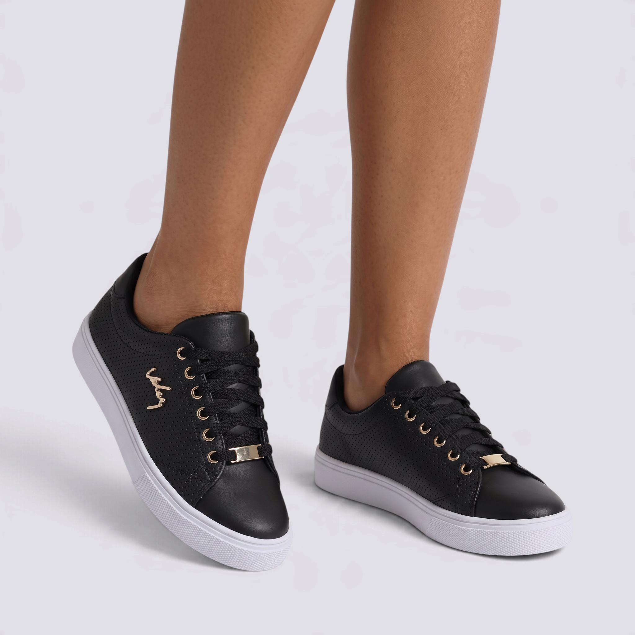 Zapatillas planas perforadas con detalle dorado en negro, vista frontal