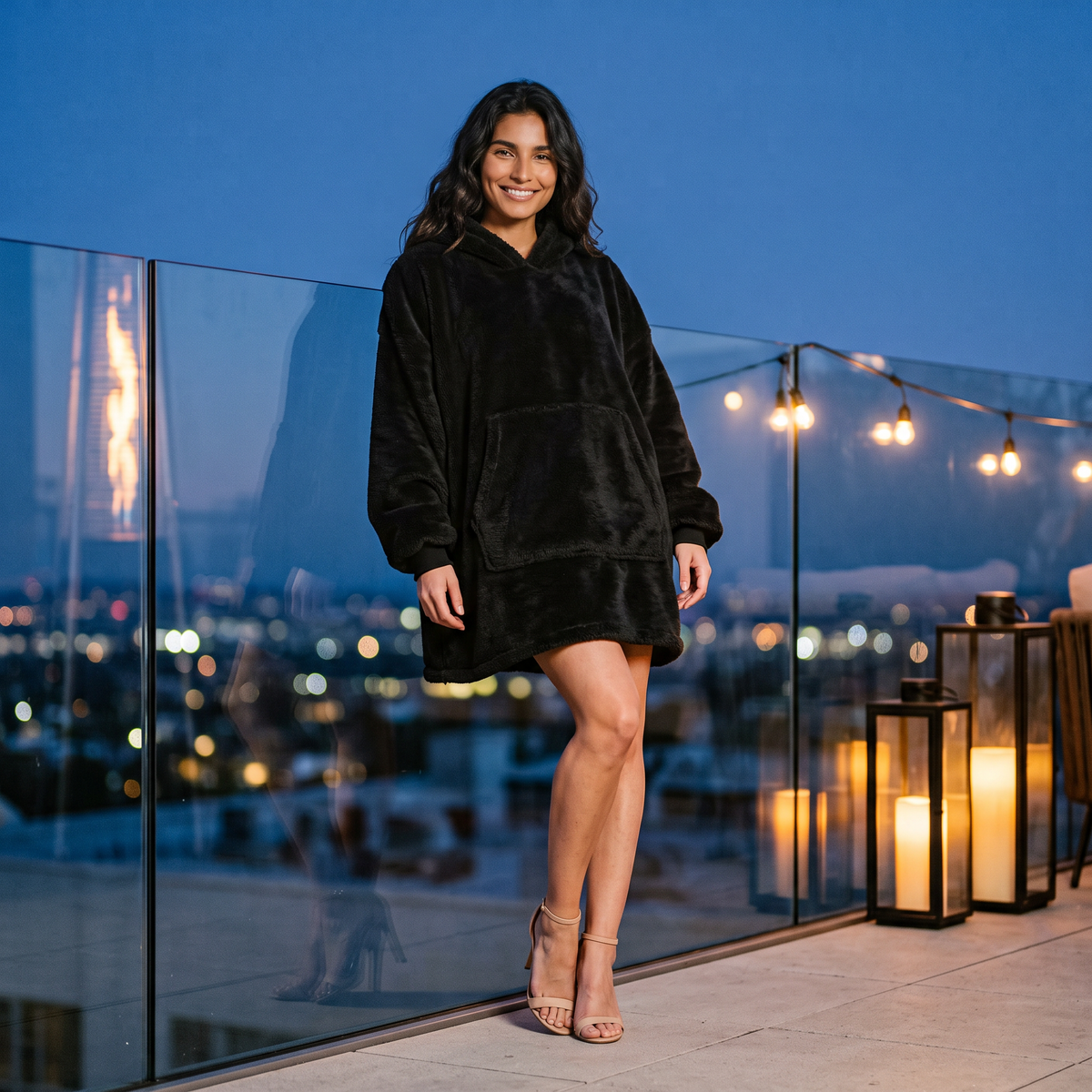 Sudadera manta de mujer oversize con capucha y bolsillo canguro color negro, look nocturno en una terraza urbana al atardecer