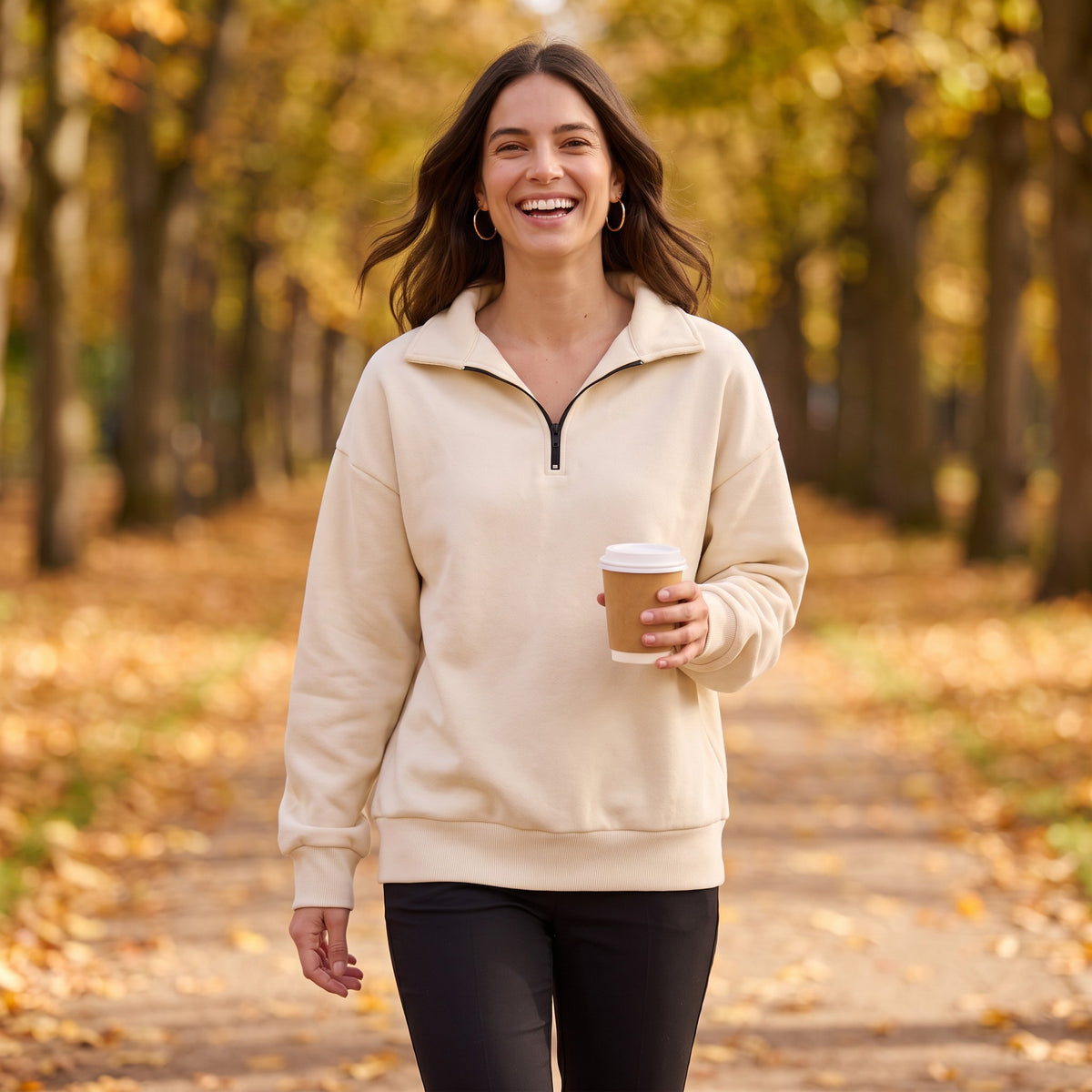 Mujer paseando por un parque en otoño con sudadera oversize de media cremallera y cuello solapa color crema