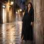 Mujer con vestido camisero largo con cuello mao y bolsillos en negro paseando por una calle empedrada de noche