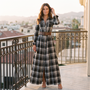 Mujer con vestido largo camisero de cuadros tartán con cinturón, cuadros negro, en una terraza al atardecer