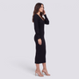 Mujer con vestido midi de punto canalé ajustado en negro, vista lateral